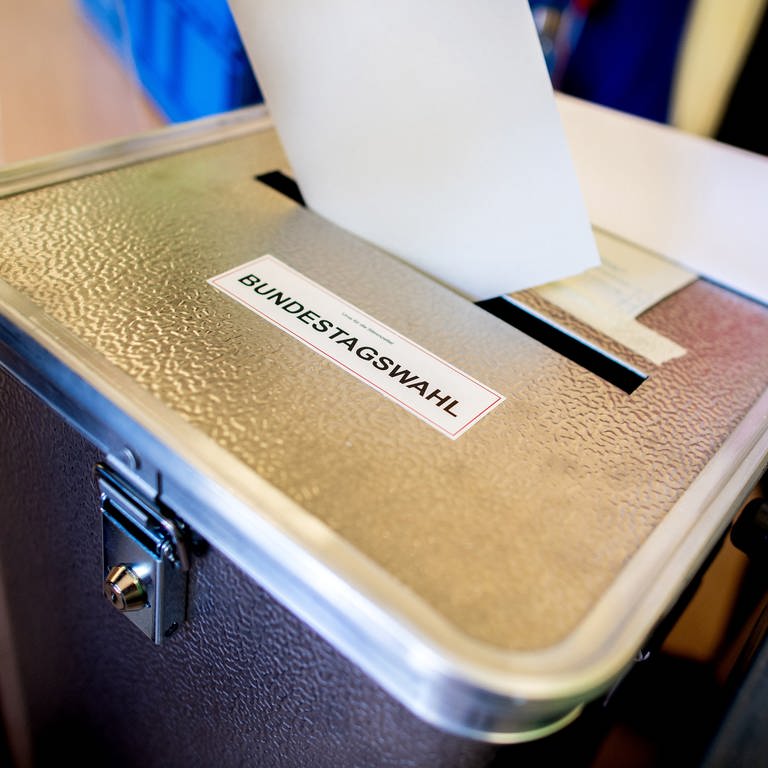 Ein Wähler wirft in einem Wahllokal seinen Stimmzettel für die Bundestagswahl in eine Wahlurne. 
