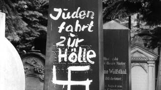 Mit einem Hakenkreuz beschmierter Grabstein auf einem jüdischen Friedhof in Bamberg 1965.
