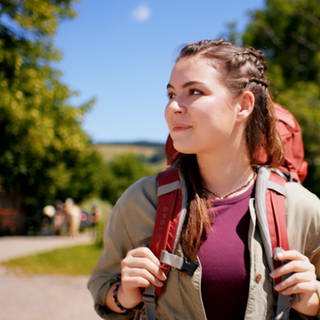 Ein Mädchen mit Rucksack in ländlicher Umgebung