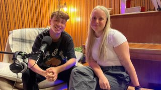 Finnel und Maria Ziffy sitzen zusammen im Tonstudio und nehmen eine Podcastfolge für we be like auf