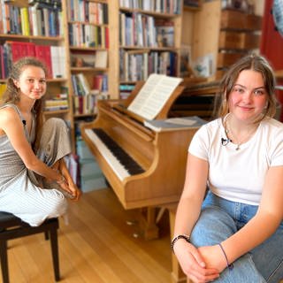 Die beiden Freundinnen Ayla und Anastassia vor einem Klavier.