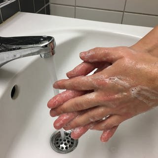 Hände werden am Waschbecken gewaschen
