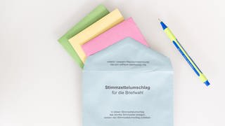 Verschiedene Stimmzettel stecken in einem Stimmzettelumschlag für die Briefwahl. 