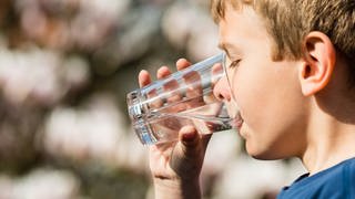 Ein Junge trinkt ein Glas Wasser