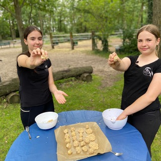 zwei Mädchen halten selbstgemachte Plätzchen in die Kamera